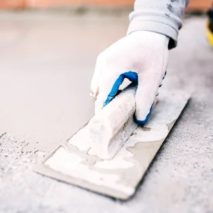 Unterstützt die Haftung der Spachtelmasse - industrial worker on construction site laying sealant for waterproofing cement - Stock-Fotografie